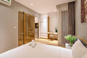 A hotel room with a bed, a desk, a chair, a wardrobe, and a painting on the wall. - The Art - Sunshine Apartment (Ho Chi Minh City)
