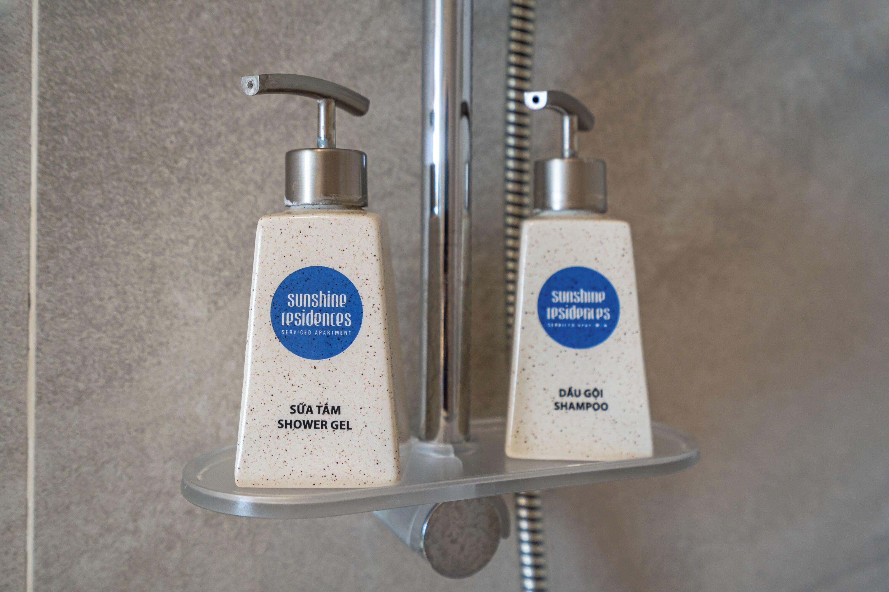Deux flacons de gel douche sur une étagère métallique dans une salle de bain.