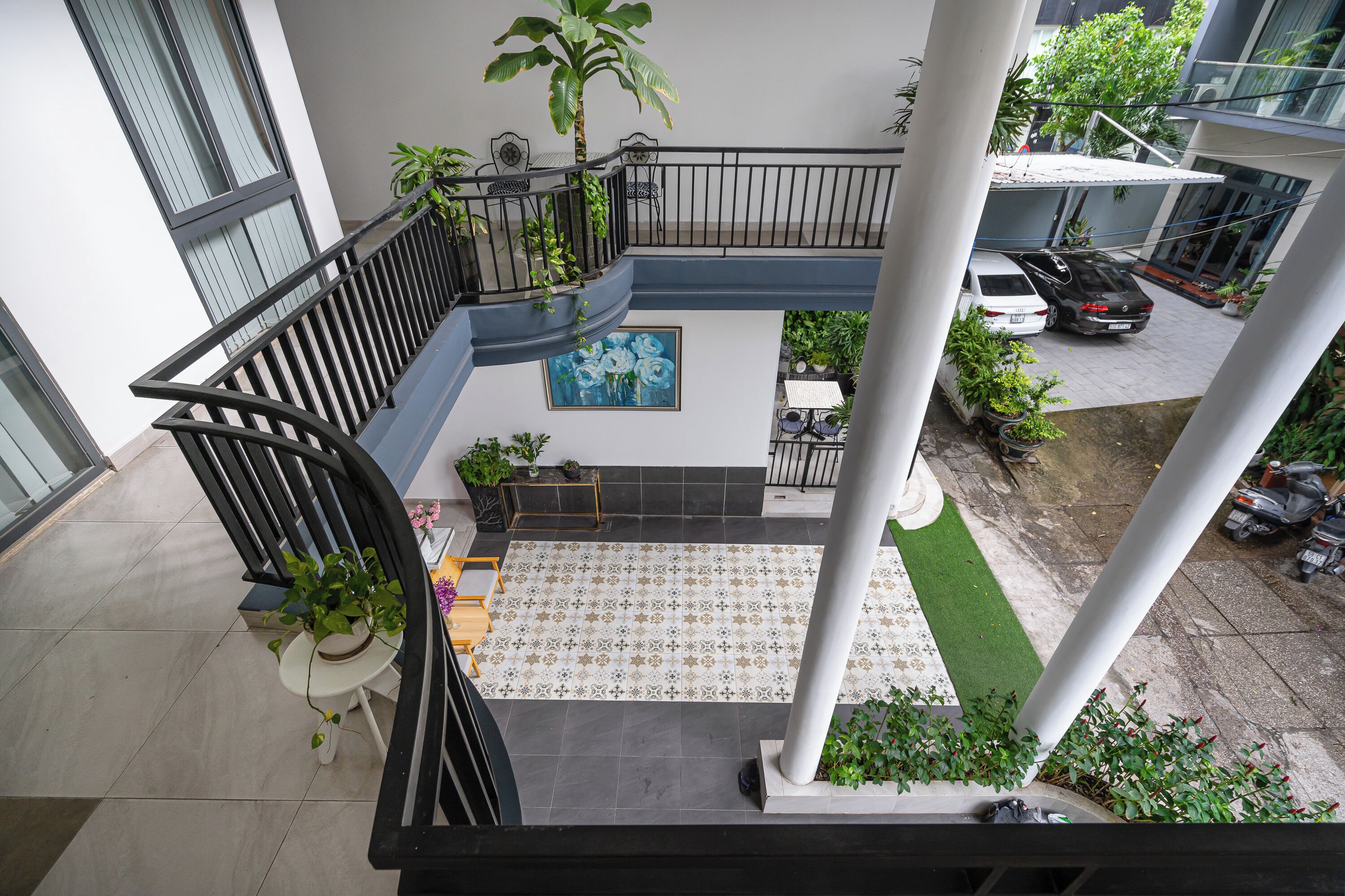 A multi-level residential building with a balcony, potted plants, and a tiled floor.