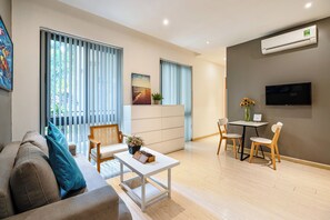 A modern living room with a sofa, a coffee table, and a dining area with chairs and a small table. - The Art - Sunshine Apartment (Ho Chi Minh City)