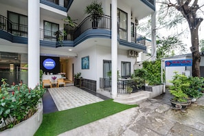 A serviced apartment complex with multiple balconies, a reception area, and a small garden.