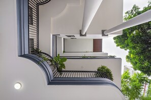 A modern building with a curved balcony, a round light fixture, and a view of greenery. - The Art - Sunshine Apartment (Ho Chi Minh City)