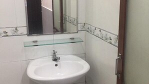 A bathroom with a white sink, a glass shelf above it, and a mirror.