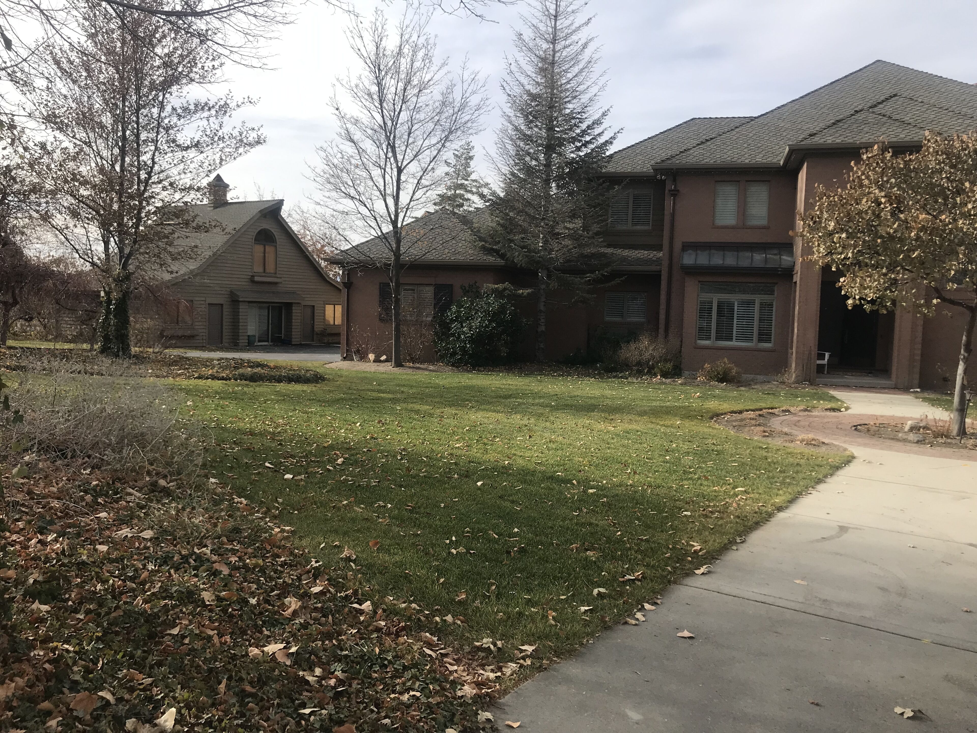 Un quartier résidentiel avec une pelouse bien entretenue, un trottoir et des maisons aux façades en briques et aux toits à deux versants.