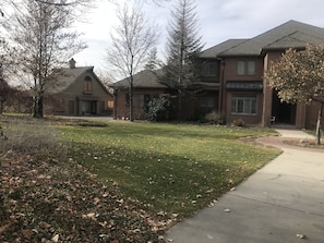 A residential area with a well-maintained lawn, a sidewalk, and houses with brick exteriors and pitched roofs.