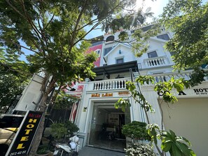 A hotel entrance with a sign reading "Hải Lâm Hotel" and a contact number.