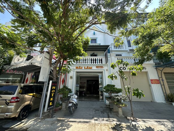 A hotel entrance with a sign reading "HÀI LÀM HOTEL" and a visible address.
