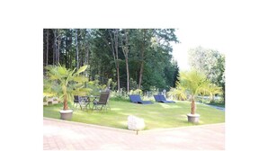 Un'area giardino con prato, due palme e due poltrone da relax.