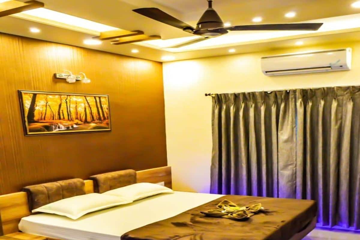 A modern bedroom with a bed, a ceiling fan, an air conditioning unit, and a painting on the wall.