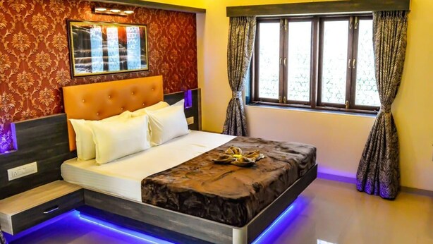 Un dormitorio moderno con una cama grande, cabecera con espejo, ventana con cortinas y un equipo de aire acondicionado.