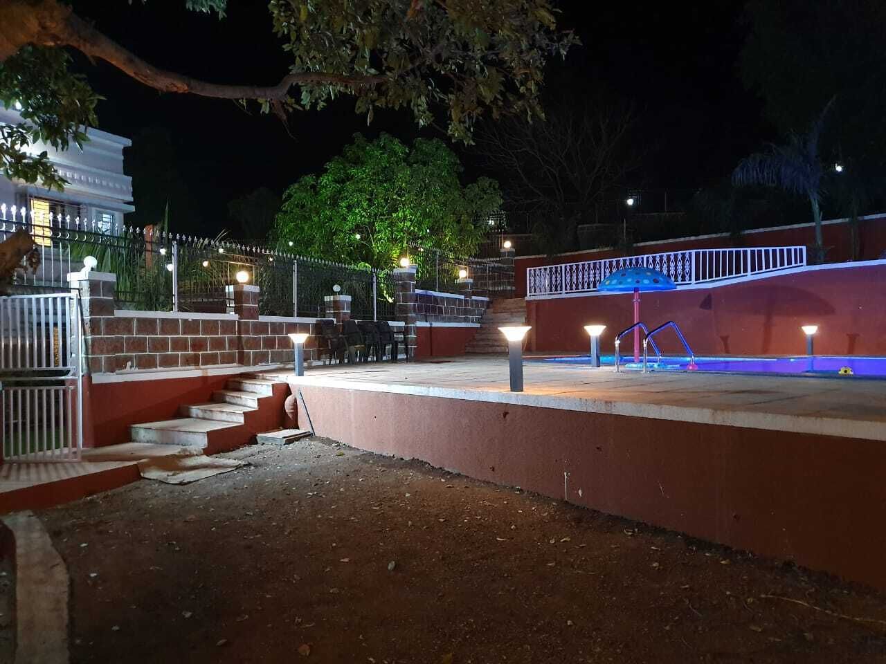 Een buitengebied bij nacht, met trappen die leiden naar een platform, omringd door een hek en verlicht door straatlantaarns.