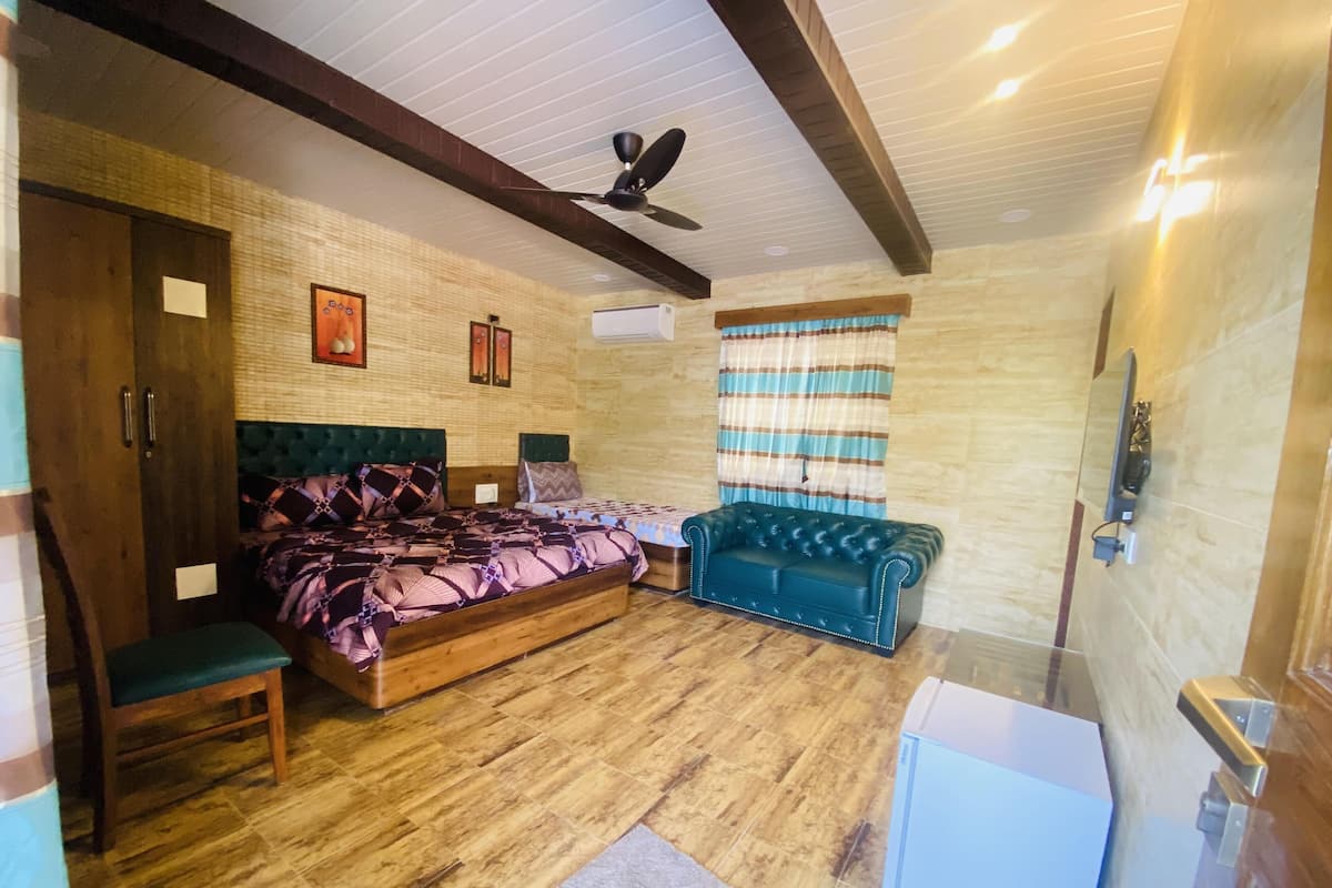 A bedroom with a bed, a sofa, a ceiling fan, and a window with curtains.