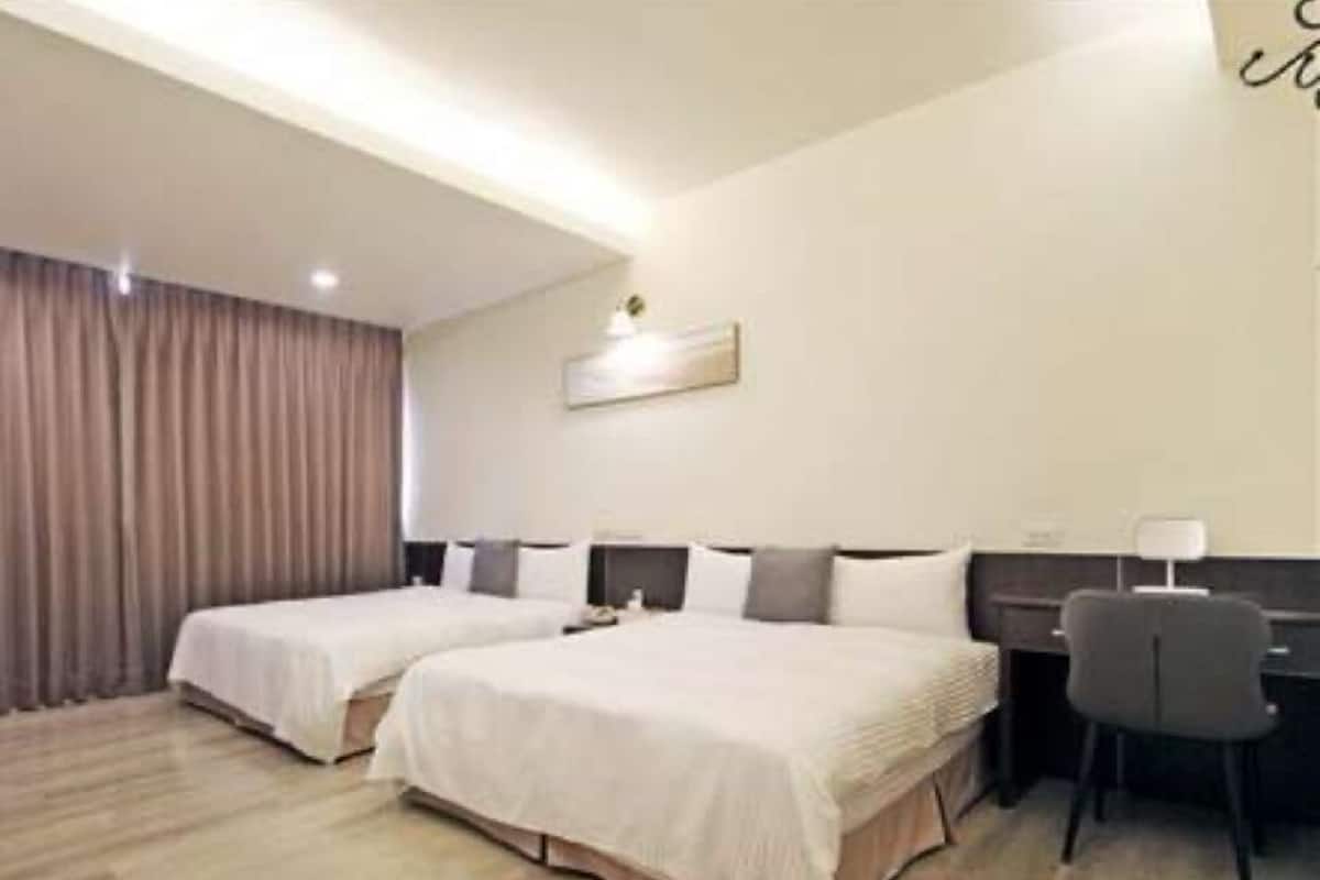 Habitación de hotel con dos camas, un escritorio y una silla.
