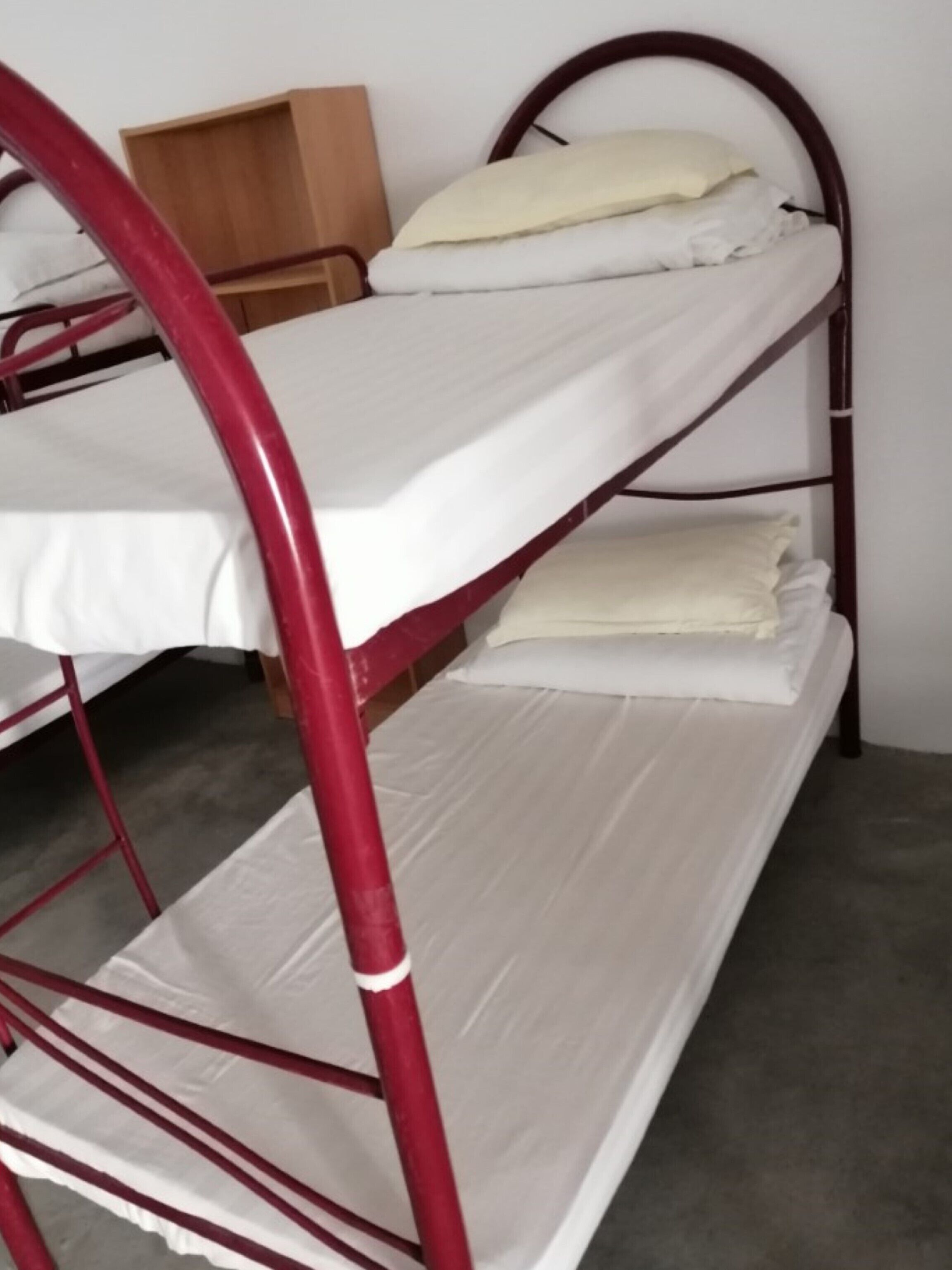Ein Etagenbett mit Holz Kopfteil, weißer Bettwäsche und einer kleinen Holzablage.