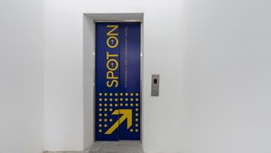 A blue elevator door with "SPOT ON" and an arrow pointing right, indicating the direction to the elevator. - Hotel O Sohotel (Pelabuhan Klang)