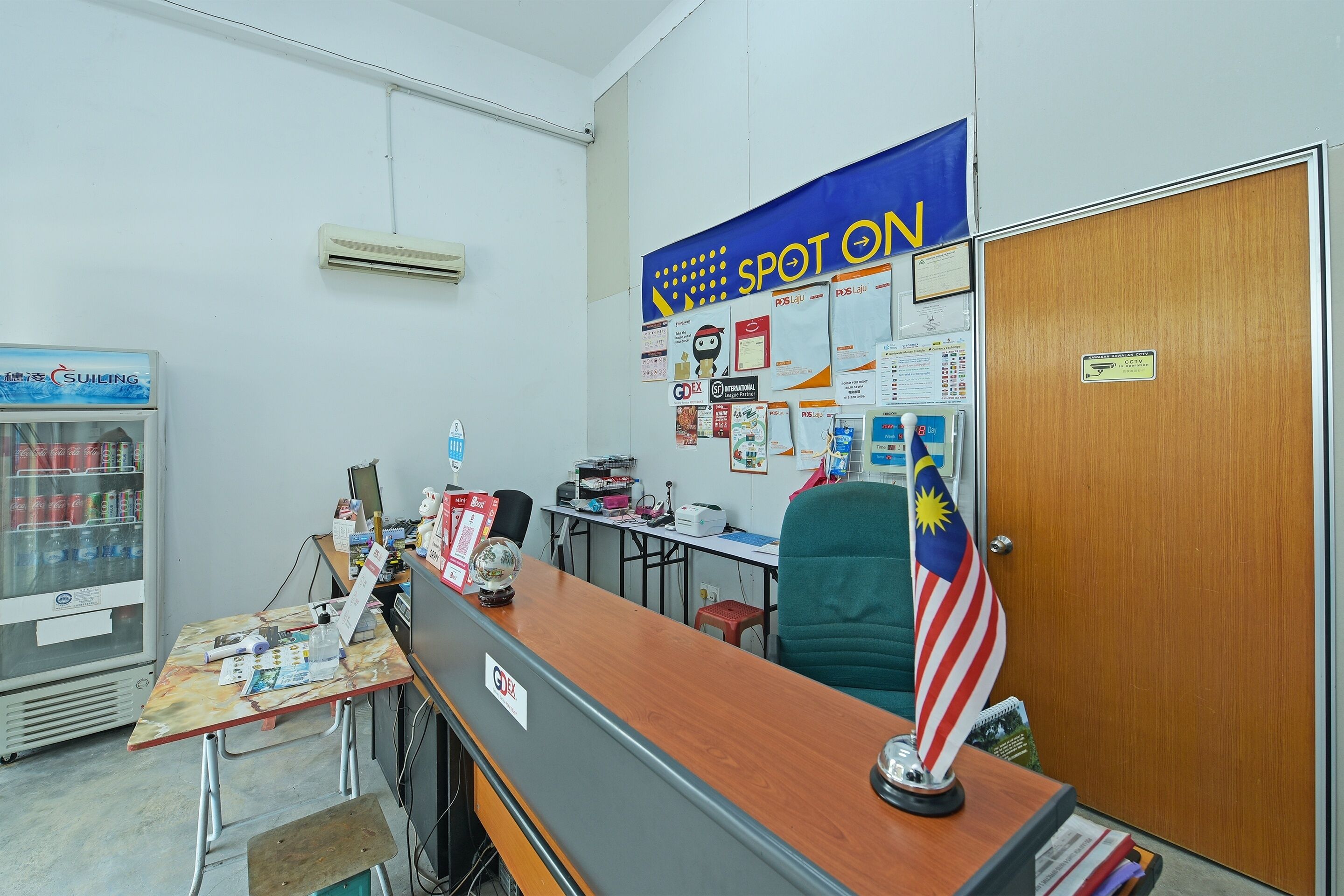 A reception area with a counter, a refrigerator, a blue banner, and a flag.