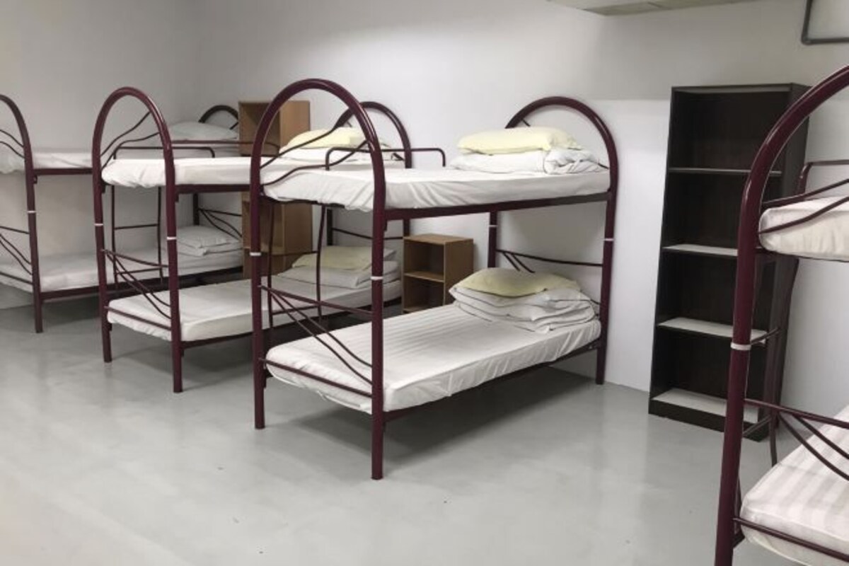 Camas literas en una habitación de paredes blancas y una estantería.