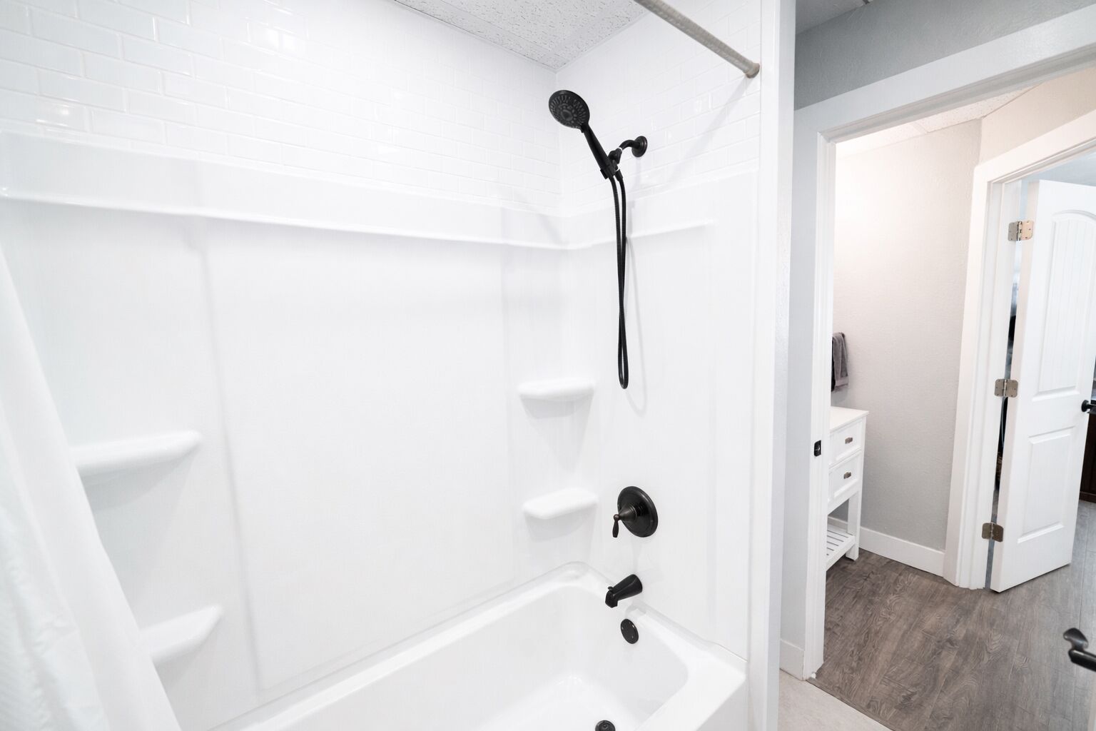 Une salle de bain moderne avec une baignoire blanche, une pomme de douche et un meuble-lavabo avec un miroir.