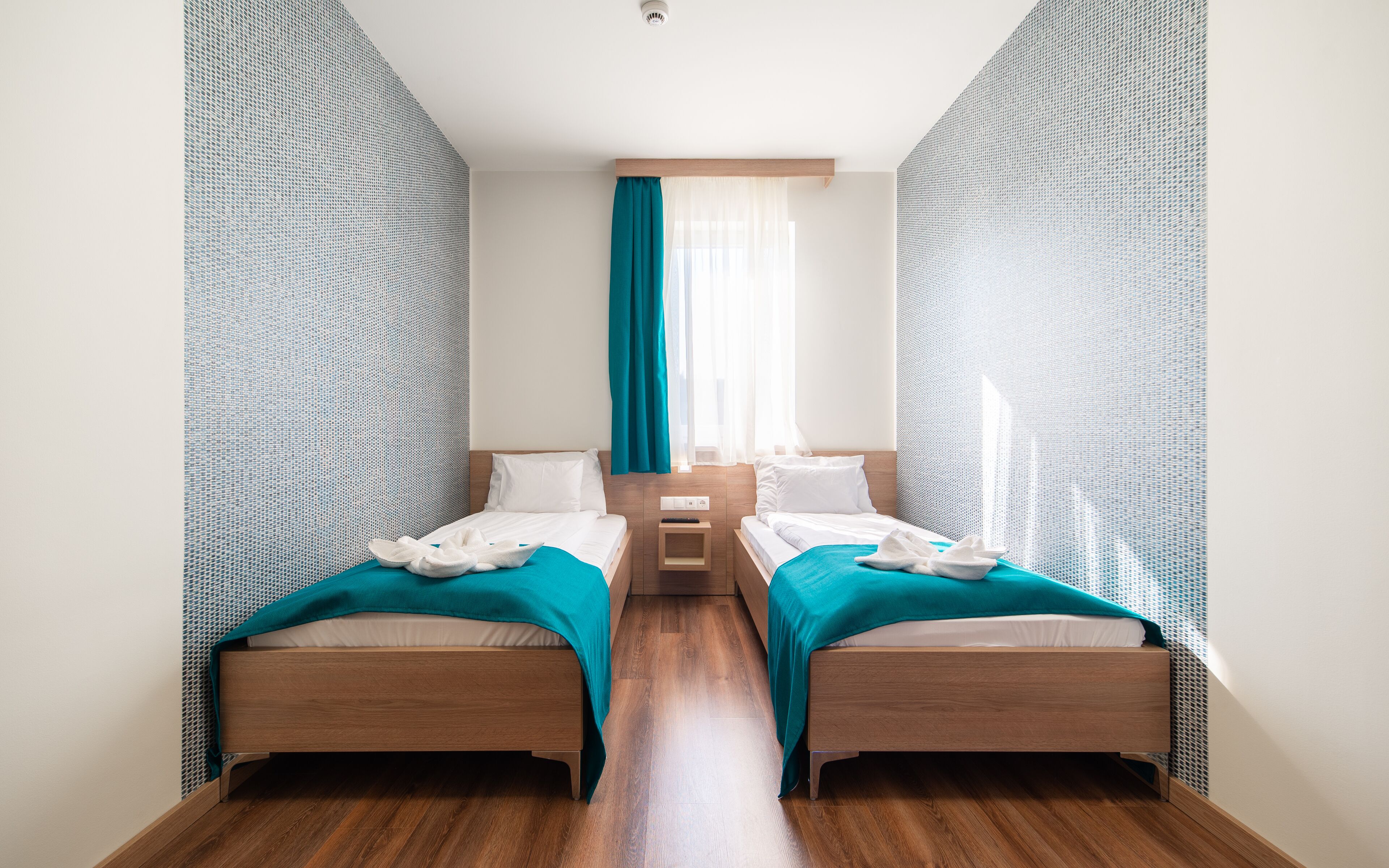 Habitación de hotel con dos camas, suelo de madera y paredes con diseño.
