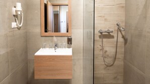 A modern bathroom with a glass-enclosed shower, a wooden vanity with a mirror, and a wall-mounted telephone. - Hotel Szeghalom (Szeghalom)