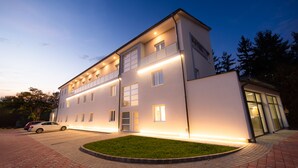 A modern hotel with a flat roof, large windows, and a well-lit entrance. - Hotel Szeghalom (Szeghalom)