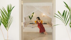 A woman in a red dress sitting on a bed with a white canopy, surrounded by potted plants. - Kirinuga Boutique Retreat (Tangalle)