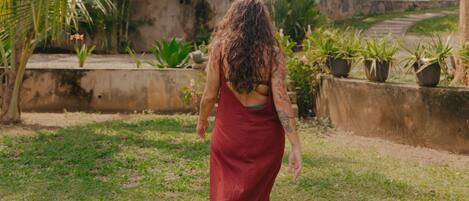 A woman walking on a path surrounded by greenery and buildings.