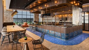 Zona de bar moderna con mesa de billar, asientos y vistas al exterior.