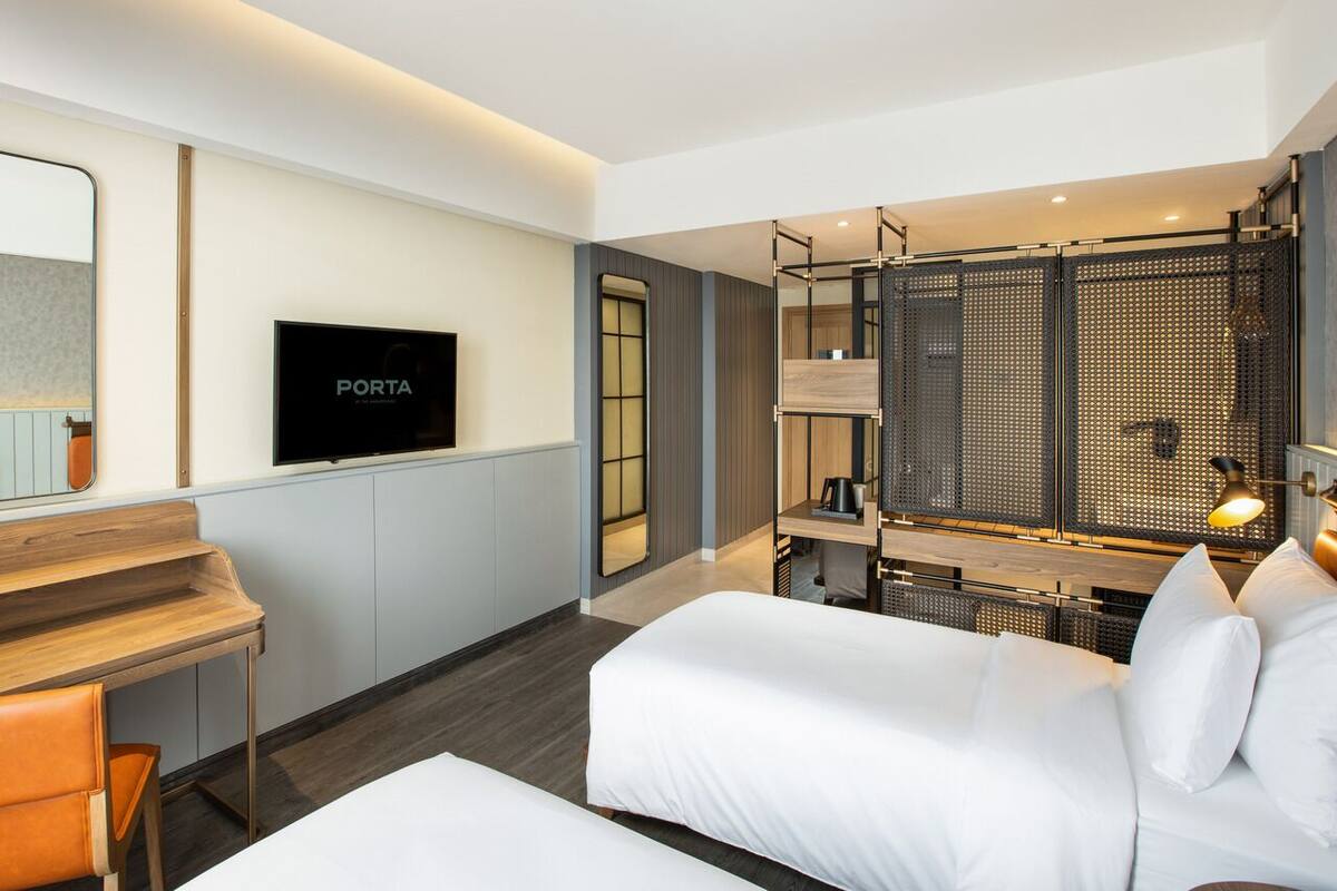 A modern hotel room with a bed, a desk, a TV, and a balcony with a view.