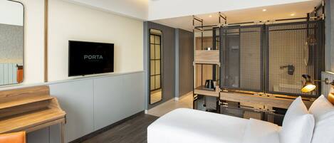 A modern hotel room with a bed, a desk, a TV, and a balcony with a view.