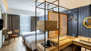 Una habitación de hotel con dos camas, un escritorio de madera, un lavamanos y un espejo.