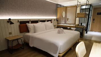 A modern hotel room with a large bed, a wooden desk, a chair, and a window with a view.