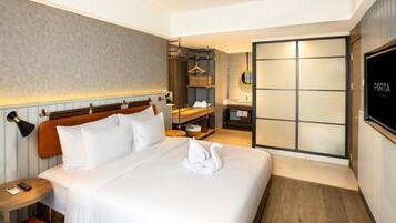 A hotel room with a large bed, a bedside table, a wardrobe, and a bathroom with a sink and mirror.