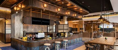 A modern bar area with a curved counter, bar stools, and a large wooden table.