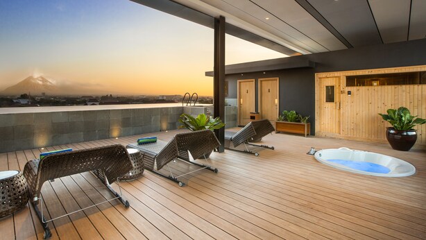 Una terraza moderna en la azotea con sillones de descanso, una bañera de hidromasaje y vistas a la montaña.