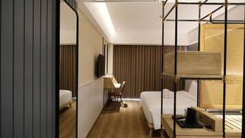 A hotel room with a bed, a desk, a chair, a TV, and a window with curtains.