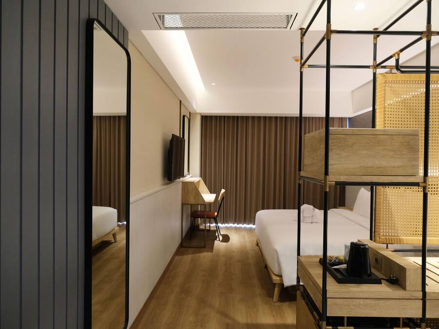 A hotel room with a bed, a desk, a chair, a TV, and a window with curtains.