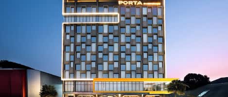 A modern hotel building with a prominent sign reading 'PORTA BY AMBARRUKMO' at the entrance.