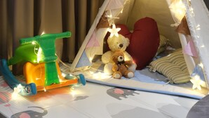 Una carpa con luces, un osito de peluche y un coche de juguete.