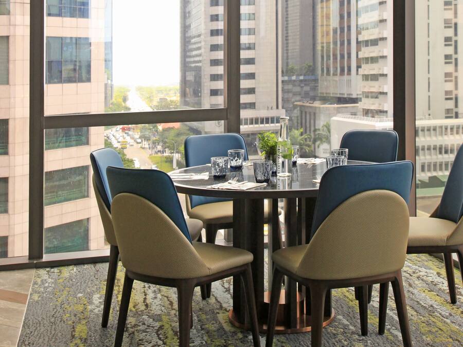 A dining area with a table set for four, large windows, and modern light fixtures.