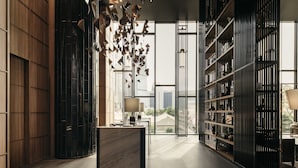 A modern interior with a marble reception desk, a large window with a city view, and a black shelving unit with decorative items. - The Clan Hotel Singapore by Far East Hospitality (Singapore)