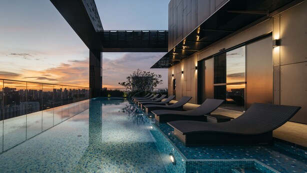 A rooftop infinity pool with lounge chairs, a city view, and a sunset. - The Clan Hotel Singapore by Far East Hospitality (Singapore)