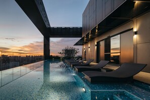 A rooftop infinity pool with lounge chairs, a city view, and a sunset. - The Clan Hotel Singapore by Far East Hospitality (Singapore)