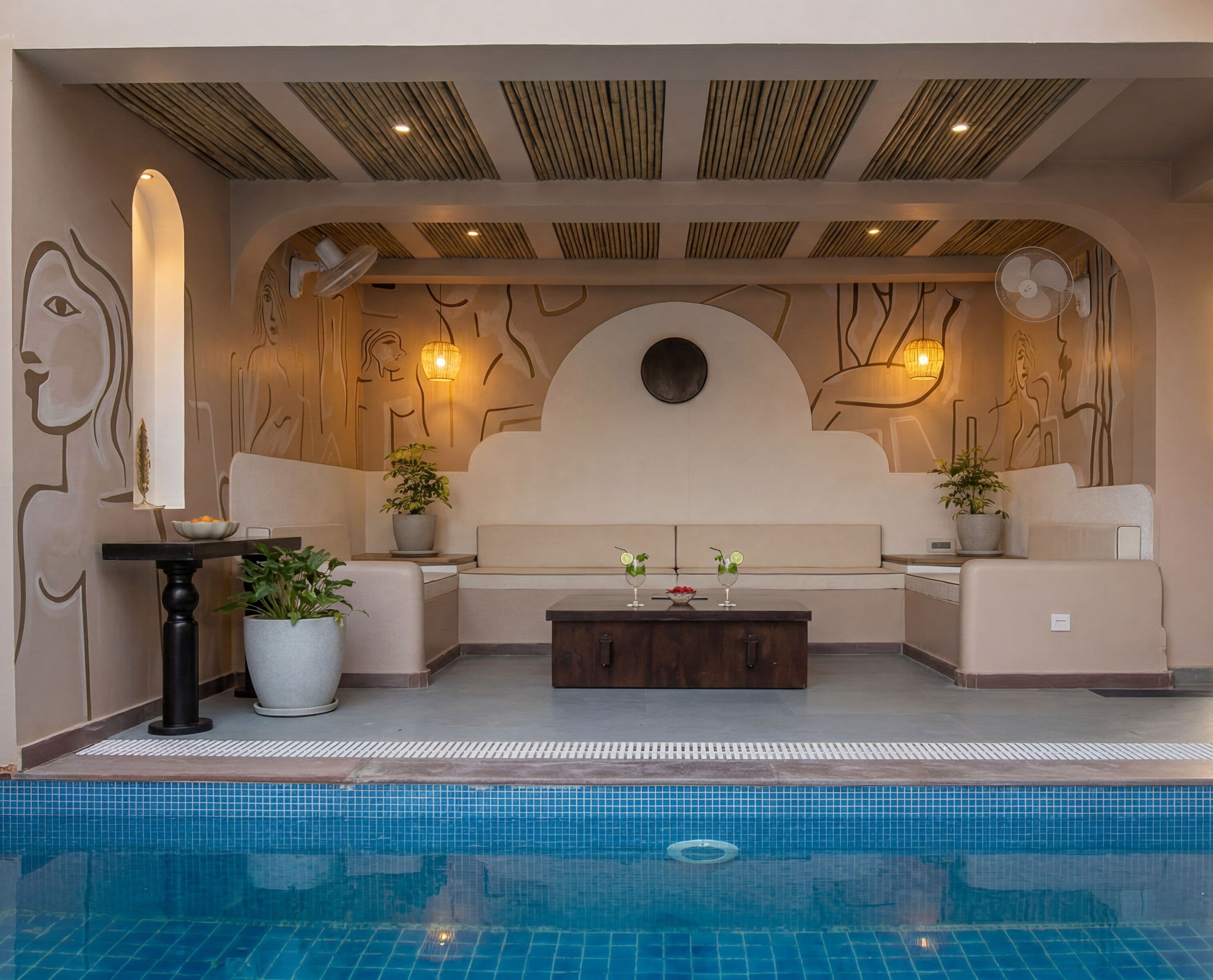 A poolside area with a seating arrangement, a table, and a potted plant.
