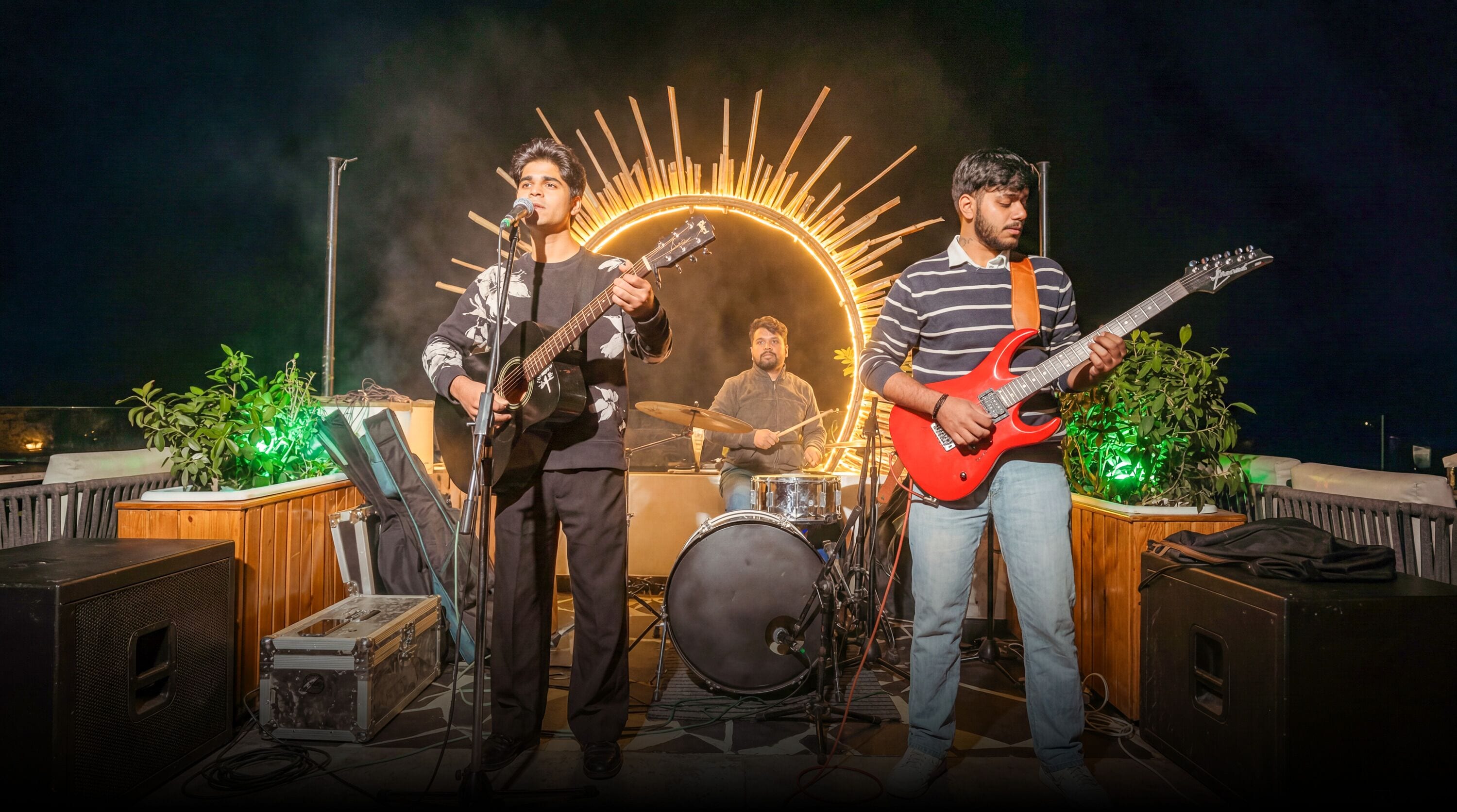 Una banda tocando en un escenario, con instrumentos musicales, una batería y un soporte para micrófono.