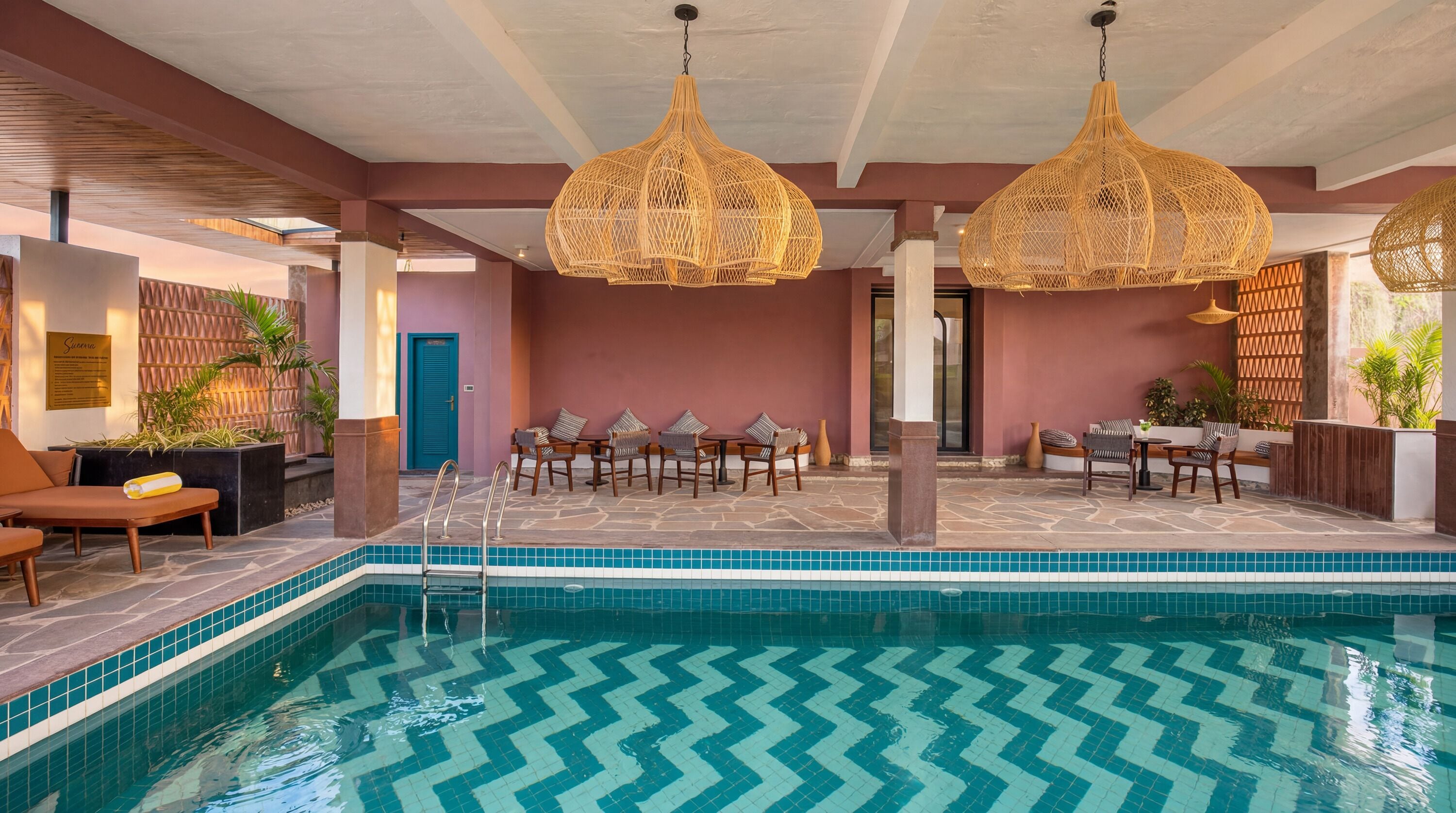 A pool area with a zigzag tile pattern, wicker pendant lights, and seating arrangements.
