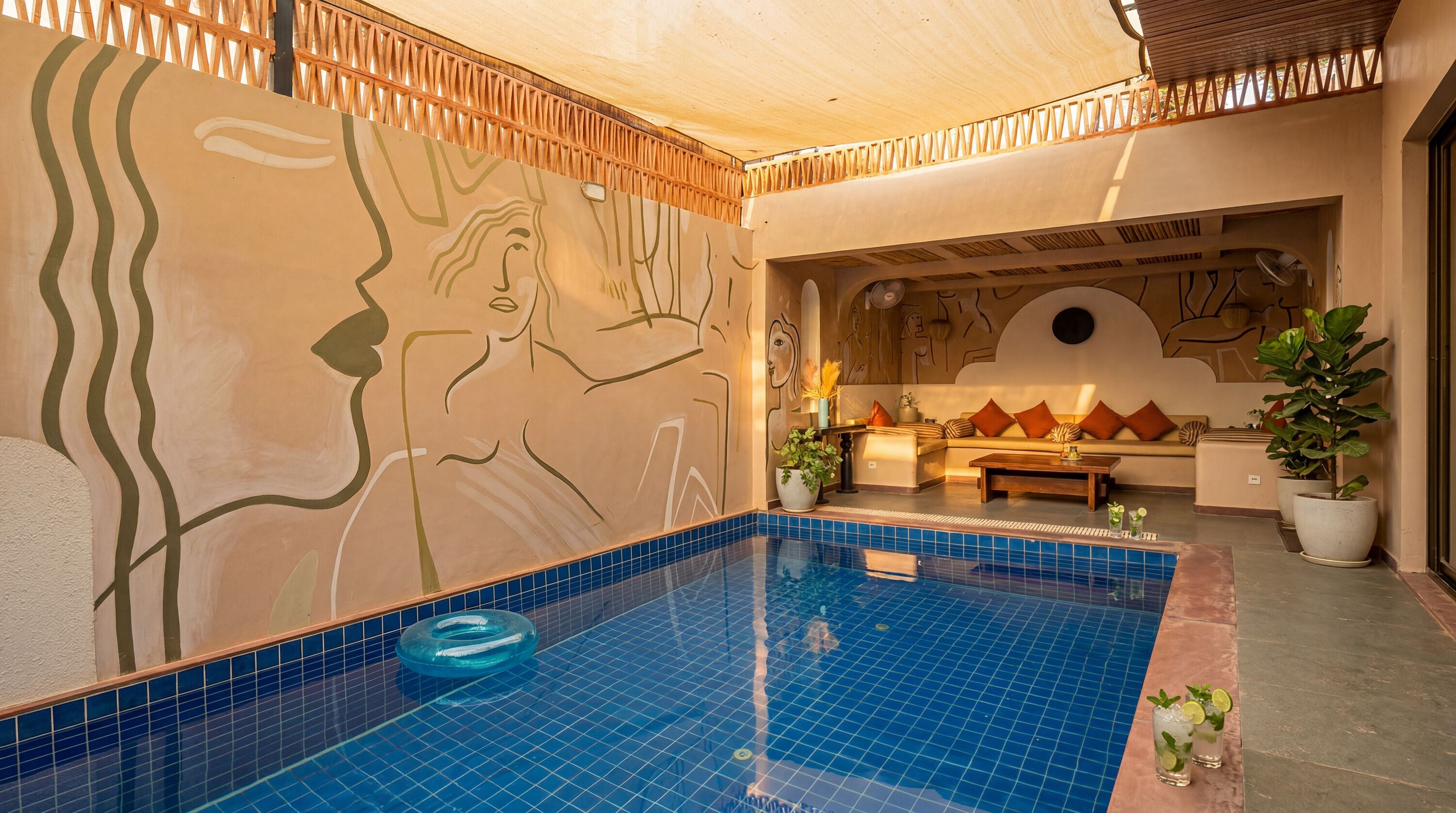 Una piscina con piastrelle azzurre, soffitto in legno e un muro con un affresco.