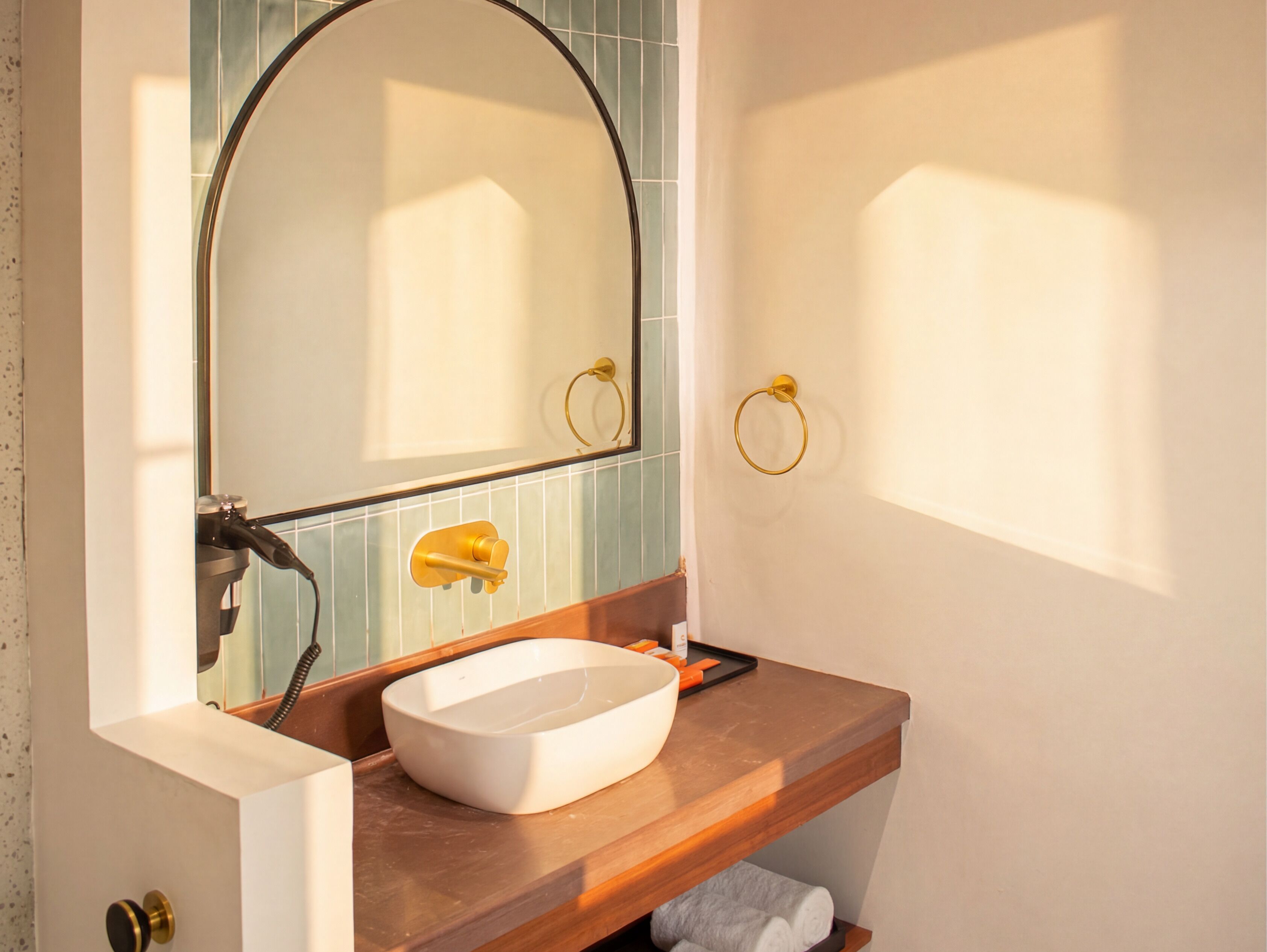 A bathroom with a white sink, a mirror, a towel ring, and a towel rack.