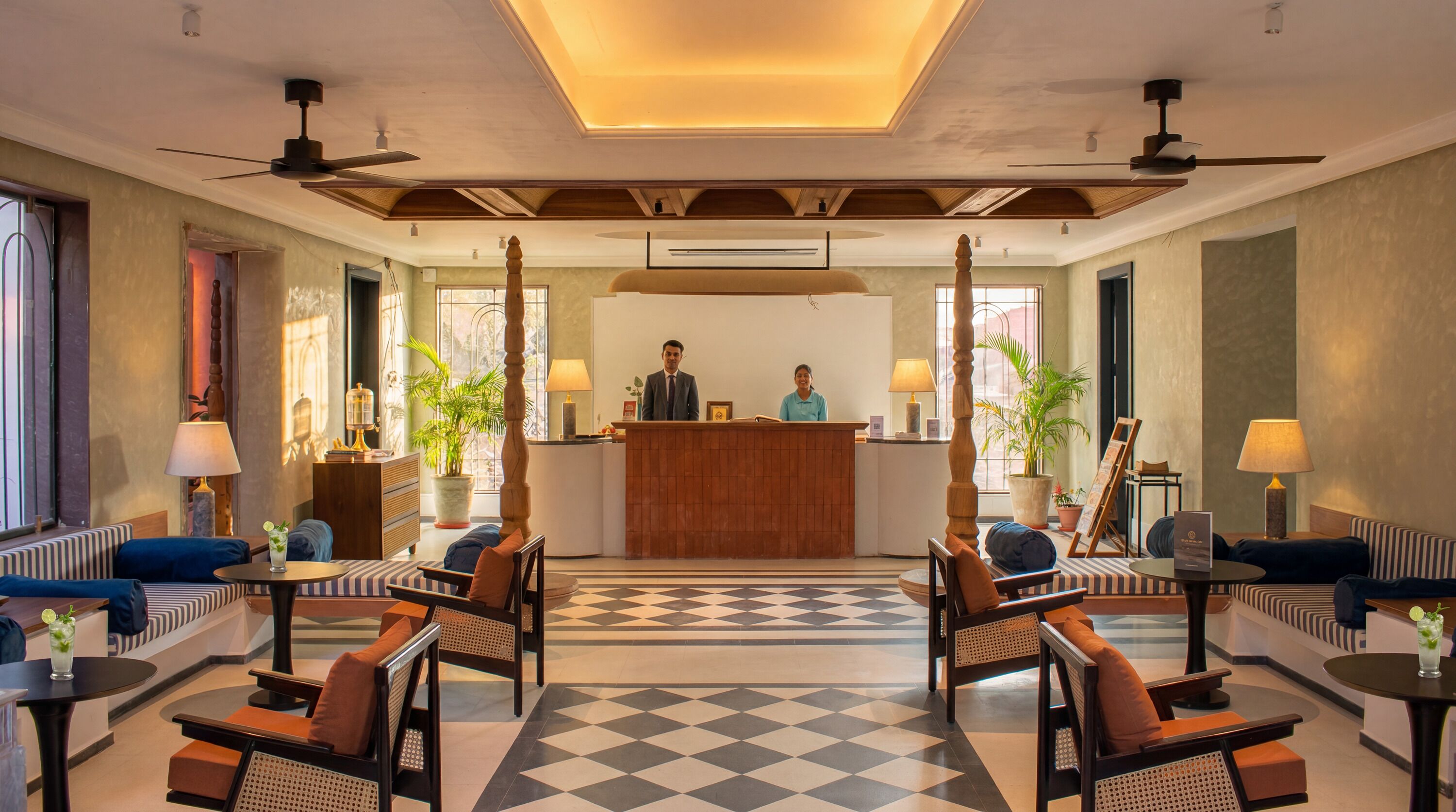 A hotel lobby with a reception desk, seating area, and a checkered floor.