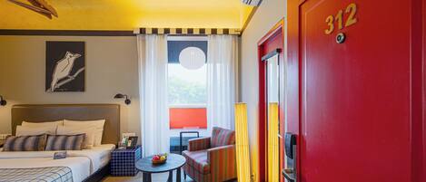 A hotel room with a bed, a sofa, a small table, and a red door with the number 312.